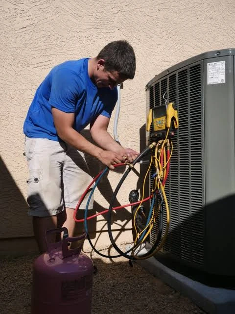 Technician checking refrigerant lines and gauges on a residential air conditioner